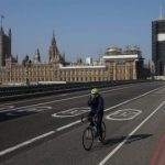 Un ciclista cruza un puente de Westminster casi vacío con las Casas del Parlamento al fondo en el centro de Londres el 9 de abril de 2020.- El primer ministro británico, Boris Johnson, comenzó el jueves un cuarto día en cuidados intensivos.
