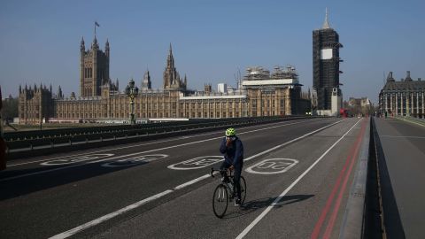 Un ciclista cruza un puente de Westminster casi vacío con las Casas del Parlamento al fondo en el centro de Londres el 9 de abril de 2020.- El primer ministro británico, Boris Johnson, comenzó el jueves un cuarto día en cuidados intensivos.