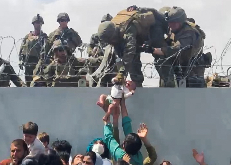 Un bebé es entregado al ejército estadounidense sobre el muro perimetral del aeropuerto para que sea evacuado, en Kabul, Afganistán, el 19 de agosto de 2021, en esta imagen fija extraída de un video obtenido de las redes sociales.  Video tomado el 19 de agosto de 2021. OMAR HAIDARI / vía REUTERS