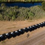 Una fila de vehículos de funcionarios del estado de Texas a orillas del Río Grande, cerca de un campamento de migrantes