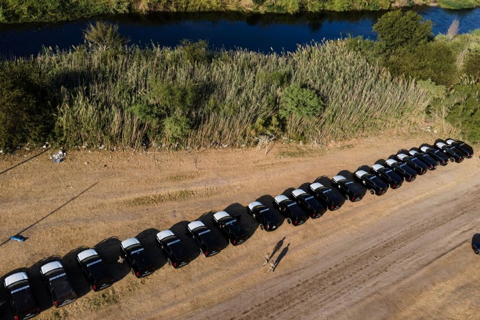 Una fila de vehículos de funcionarios del estado de Texas a orillas del Río Grande, cerca de un campamento de migrantes