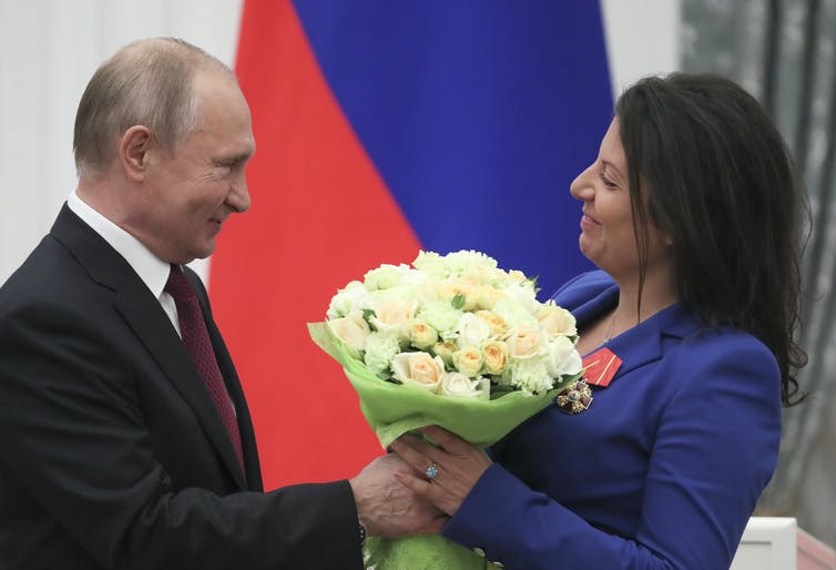 El presidente ruso, Vladimir Putin, presenta a la editora en jefe de RT, Margarita Simonyan, un ramo de flores.