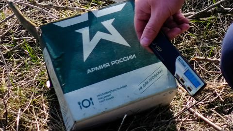 Un soldado ucraniano sostiene un medidor de radiación contra un paquete de raciones militares rusas.