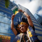 Un miembro de la tribu potiguara sostiene una copia de la constitución brasileña durante una protesta contra la violencia que sufre el pueblo yanomami.