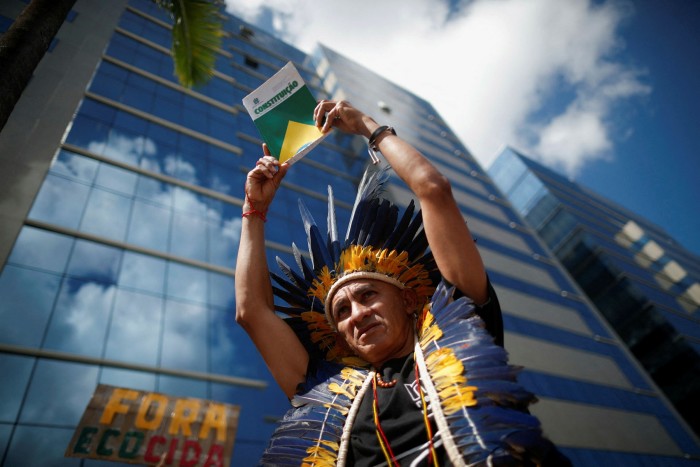 Un miembro de la tribu potiguara sostiene una copia de la constitución brasileña durante una protesta contra la violencia que sufre el pueblo yanomami.