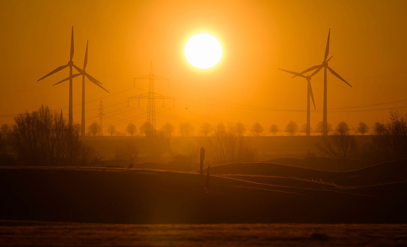 El sol sale entre turbinas eólicas y líneas eléctricas de alto voltaje en la región de Hannover, Alemania, el 8 de marzo.