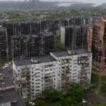 Edificios residenciales dañados en Mariupol, con la planta siderúrgica Azovstal al fondo en mayo de 2022. Las autoridades de la RPD dijeron que las fuerzas rusas capturaron a los tres hombres en la ciudad portuaria en abril.