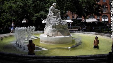 Un peatón pasa mientras los niños juegan en una fuente en el centro de la ciudad de Toulouse, en el suroeste de Francia, el 16 de junio de 2022.