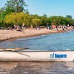 Bote pequeño con el logotipo de la ciudad de Toronto junto a una playa en las islas de Toronto