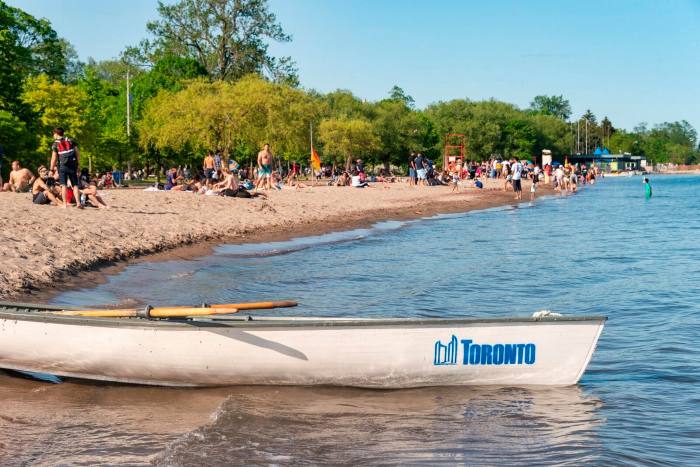 Bote pequeño con el logotipo de la ciudad de Toronto junto a una playa en las islas de Toronto