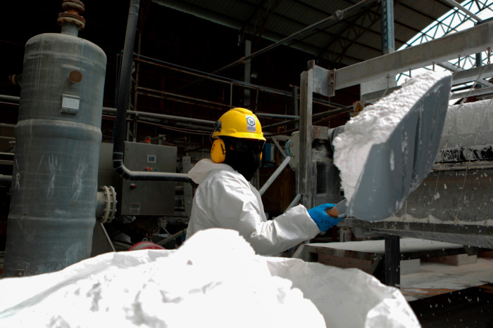 Un trabajador usa una pala para almacenar carbonato de litio en una bolsa en la planta piloto de Llipi en el salar de Uyuni en agosto.