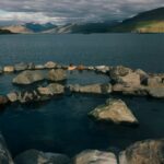 La gente se sienta en el agua de una piscina con borde de roca junto a un fiordo