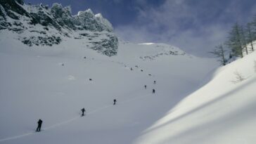 Figuras vistas en un valle nevado bajo un cielo azul