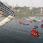 Los trabajadores de emergencia en botes buscan en las aguas debajo del puente Morbi colapsado en el estado de Gujarat.