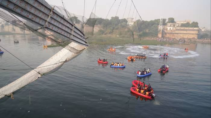 Los trabajadores de emergencia en botes buscan en las aguas debajo del puente Morbi colapsado en el estado de Gujarat.