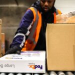 Un empleado de FedEx carga paquetes en un contenedor de avión