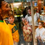 Los visitantes miran la estatua de tamaño natural de Pelé con una camiseta amarilla brillante de Brasil, con el número 10 estampado en la parte posterior, exhibida en una vitrina en el Museo Pelé en Santos, Brasil, el viernes 30 de diciembre de 2022.