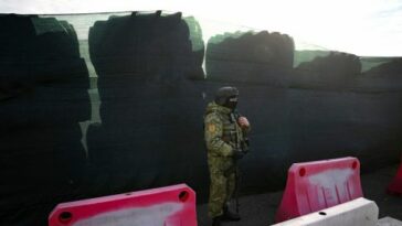 Un guardia fronterizo bielorruso vigila junto a una barricada hecha con neumáticos de camiones en el cruce fronterizo de Divin entre Bielorrusia y Ucrania en la región de Brest el 15 de febrero de 2023.