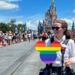 Un fotógrafo de Walt Disney World sostiene un recorte de Mickey Mouse con los colores del arcoíris del Orgullo