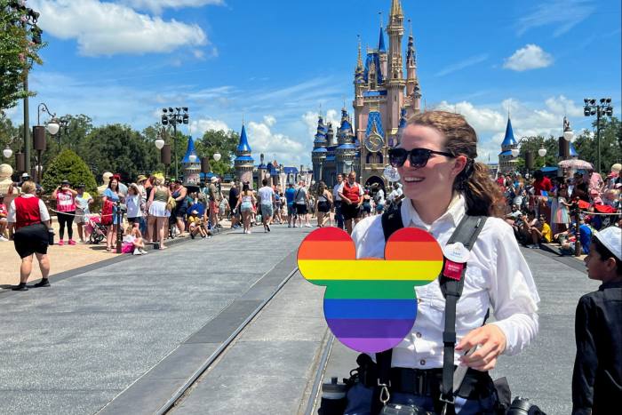 Un fotógrafo de Walt Disney World sostiene un recorte de Mickey Mouse con los colores del arcoíris del Orgullo