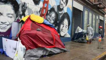 Se ven tiendas de campaña para personas sin hogar y una mujer sin hogar cerca del distrito de Tenderloin de la ciudad.