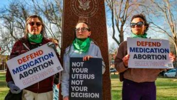 Tres miembros del grupo Marcha de Mujeres protestan en apoyo del acceso a medicamentos para el aborto frente al Palacio de Justicia Federal en Amarillo, Texas.