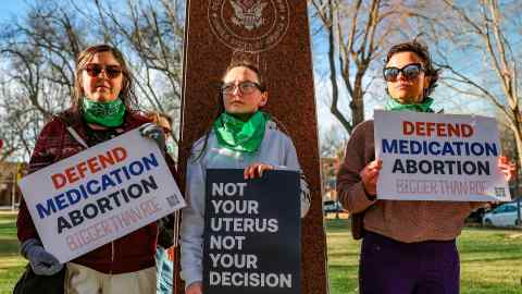 Tres miembros del grupo Marcha de Mujeres protestan en apoyo del acceso a medicamentos para el aborto frente al Palacio de Justicia Federal en Amarillo, Texas.