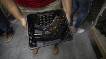 Un instructor sostiene una canasta de pistolas para los miembros que ingresan al campo de tiro de un club de tiro de Río de Janeiro.