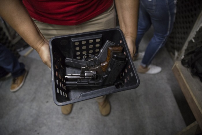 Un instructor sostiene una canasta de pistolas para los miembros que ingresan al campo de tiro de un club de tiro de Río de Janeiro.