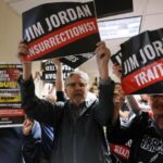Los manifestantes sostienen carteles que denuncian a Jim Jordan, el miembro republicano de la Cámara que preside la audiencia del lunes.