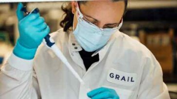 Una persona con una bata de laboratorio con el logotipo del Grial realiza una investigación.