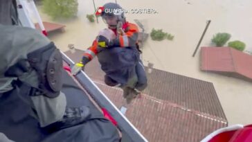 Esta foto proporcionada por la guardia costera italiana muestra a los rescatistas salvando a un hombre del techo de una casa inundada, en el área de la ciudad de Faenza.