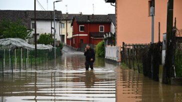 Un residente habla por teléfono mientras camina el domingo por una calle inundada en el pueblo de Carde, Cuneo, cerca de Turín, en el noroeste de Italia.