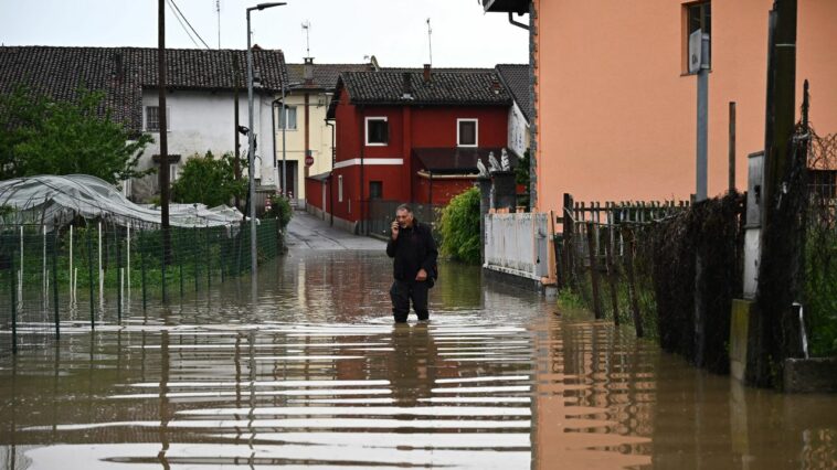 Un residente habla por teléfono mientras camina el domingo por una calle inundada en el pueblo de Carde, Cuneo, cerca de Turín, en el noroeste de Italia.