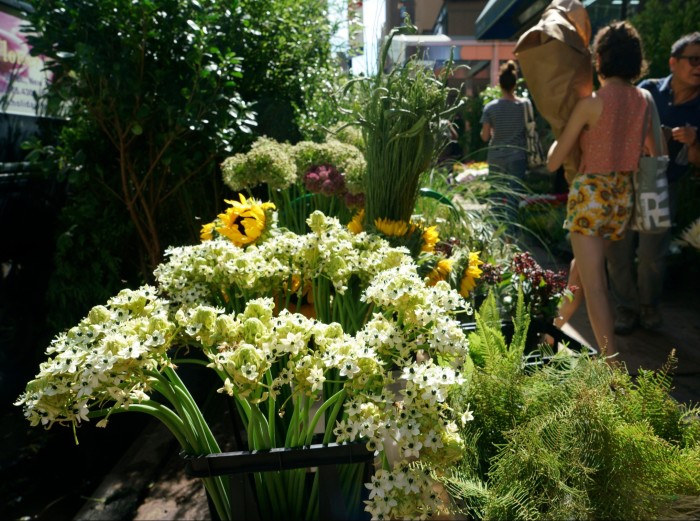 Racimos de narcisos blancos y girasoles, así como otras plantas, en un puesto en el Distrito de las Flores de Nueva York