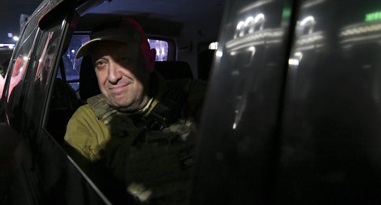 Un hombre sonriente en el asiento trasero de un auto.