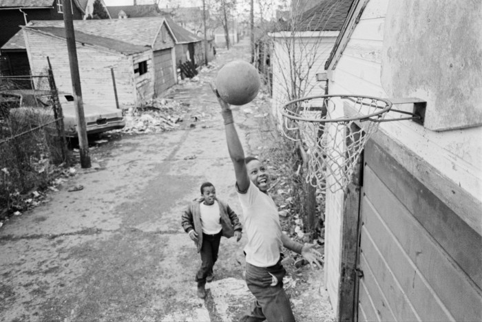 Dos niños juegan baloncesto en la calle en un barrio destartalado de una ciudad estadounidense