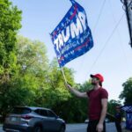 Los manifestantes sostienen banderas de la ex campaña de Donald Trump fuera del evento de campaña de DeSantis en Manchester, New Hampshire, el jueves.