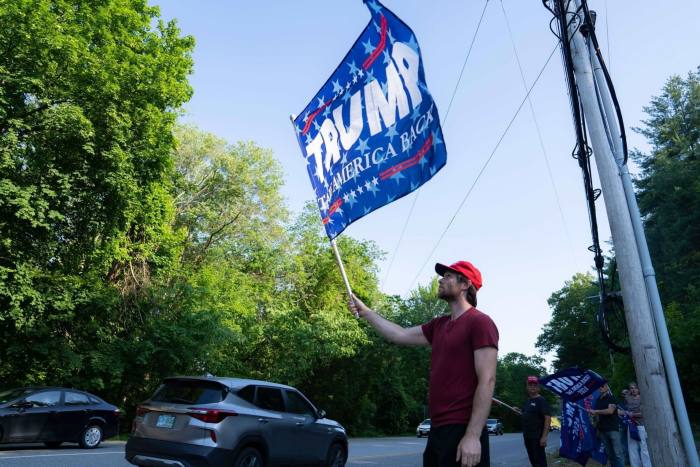 Los manifestantes sostienen banderas de la ex campaña de Donald Trump fuera del evento de campaña de DeSantis en Manchester, New Hampshire, el jueves.