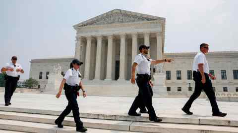 Los oficiales de policía limpian a las personas de la acera frente al edificio de la Corte Suprema de EE. UU.