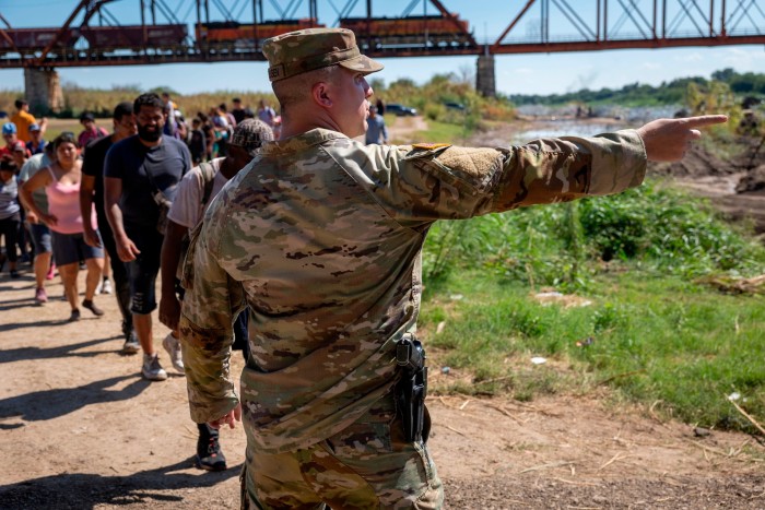 Un soldado de la Guardia Nacional de Texas señala a los migrantes hacia un puesto de control de la Patrulla Fronteriza de EE. UU.
