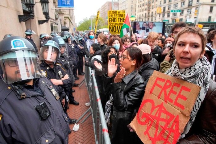 La policía antidisturbios hace guardia mientras los manifestantes corean consignas fuera del campus de Columbia.