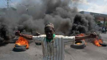 Un manifestante se encuentra entre neumáticos quemados durante una manifestación en Haití.