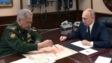 El ministro de Defensa ruso, Sergei Shoigu, sentado frente a Vladimir Putin, señala un mapa.