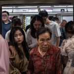 Dos mujeres, una joven y otra mucho mayor, salen de un abarrotado tren del metro de Pekín.