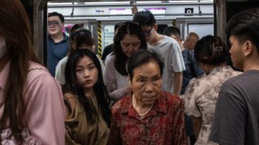 Dos mujeres, una joven y otra mucho mayor, salen de un abarrotado tren del metro de Pekín.