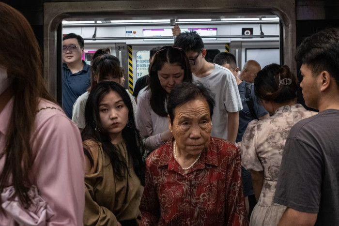 Dos mujeres, una joven y otra mucho mayor, salen de un abarrotado tren del metro de Pekín.