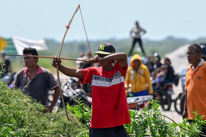 Un miembro de la comunidad indígena Yukpa armado con un arco y una flecha bloquea la carretera exigiendo hablar con María Corina Machado durante su viaje por carretera cerca de Maracaibo