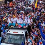 El candidato presidencial Edmundo González y la líder opositora María Corina Machado saludan a sus partidarios desde la parte trasera de un camión durante un mitin de campaña en Maracaibo el martes