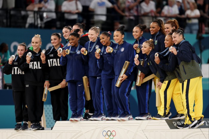 Gimnastas de Italia, Estados Unidos y Brasil celebran tras concluir la final por equipos en París, Francia